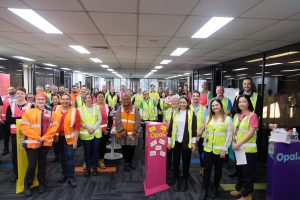 A crowd gather for a photo all dressed in high vis vests ranging from fluro orange, pink and yellow.
